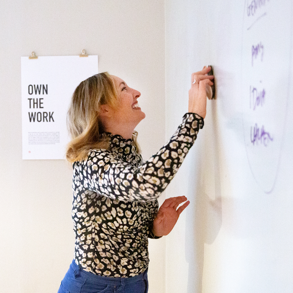 A smiling brand writer workshops her ideas on a whiteboard