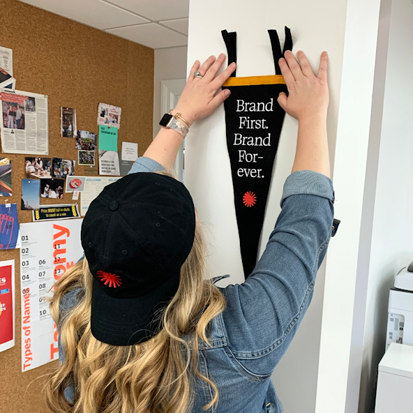 A Focus Lab employee hangs up a pennant reading "Brand First. Brand Forever."