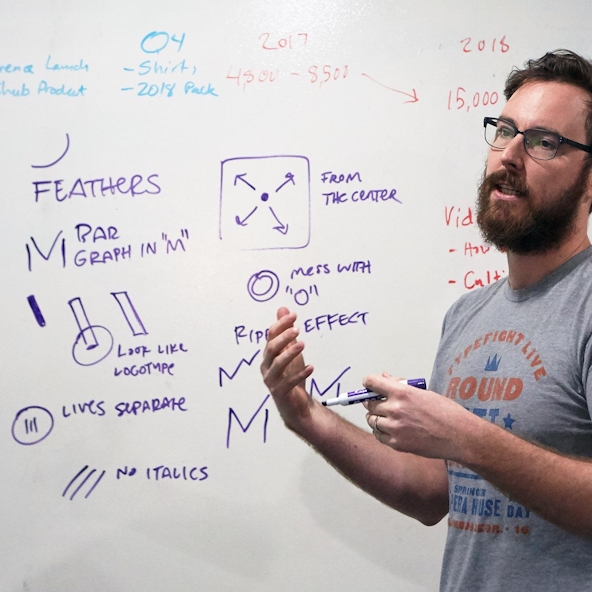 A designer talks through visual ideas in front of a whiteboard.